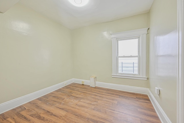 spare room with baseboards and light wood finished floors
