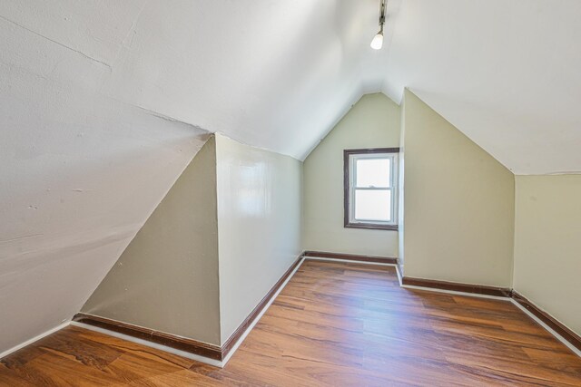 additional living space with baseboards, vaulted ceiling, and wood finished floors