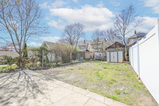 view of yard featuring a fenced backyard, a storage unit, an outdoor structure, and a residential view