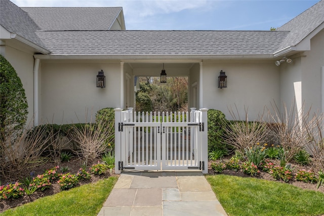 11 Morgan Ln, Locust Valley, NY 11560 - doorway to property with roof with shingles, stucco siding, a gate, and fence