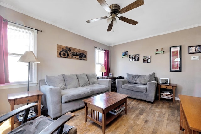 living area with crown molding, light wood-style flooring, and a ceiling fan