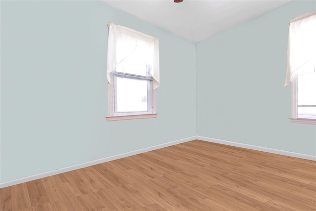spare room with light wood finished floors, a ceiling fan, and baseboards