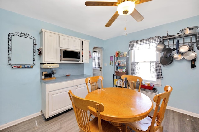 dining area with light wood-style flooring, baseboards, and ceiling fan