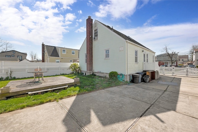 view of home's exterior with a wooden deck, a chimney, and fence
