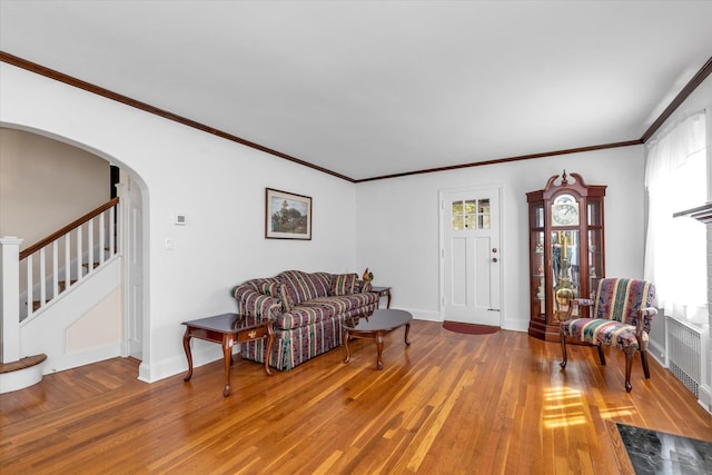 living area featuring stairway, ornamental molding, and wood finished floors