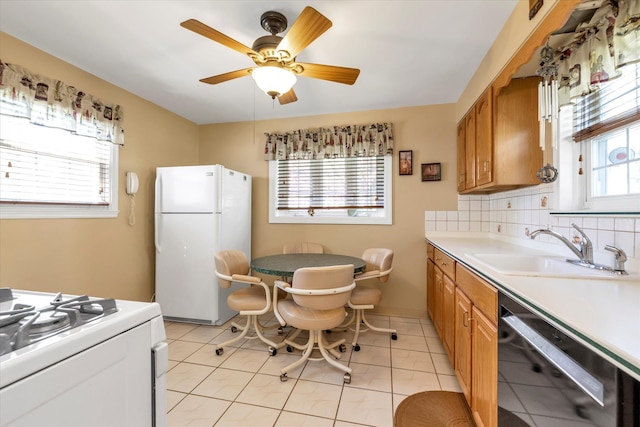 kitchen with a sink, brown cabinets, white appliances, and light countertops