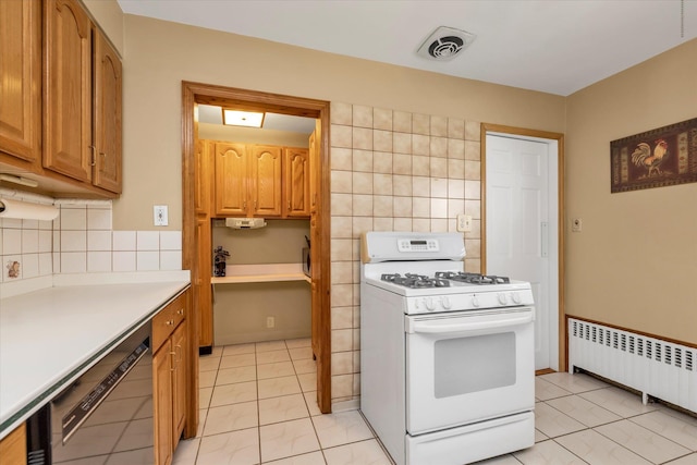kitchen featuring white gas range, visible vents, light tile patterned floors, dishwashing machine, and radiator