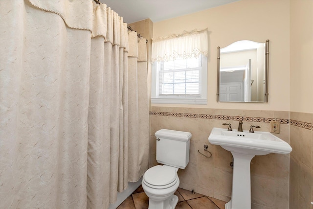 bathroom featuring tile patterned floors, wainscoting, toilet, and tile walls