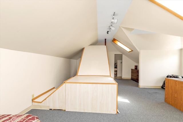 unfurnished bedroom featuring rail lighting, carpet flooring, and lofted ceiling with skylight