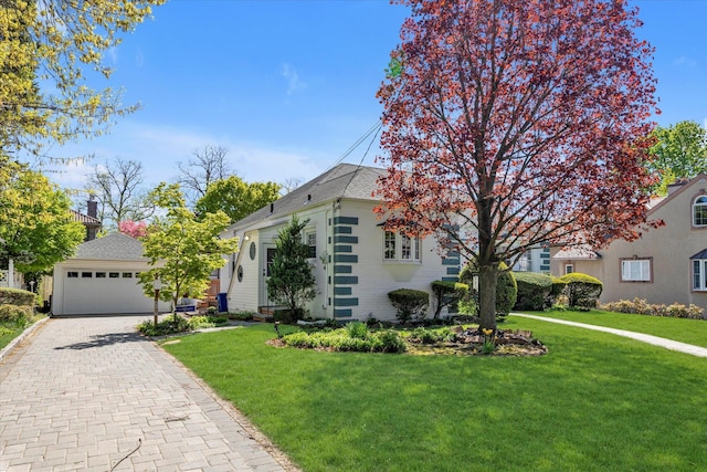 view of front of house featuring a detached garage, brick siding, and a front lawn