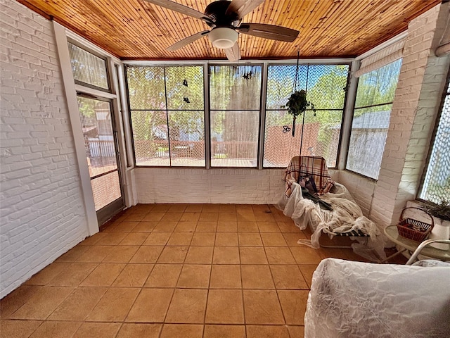 sunroom / solarium with a ceiling fan, brick wall, wood ceiling, and tile patterned flooring