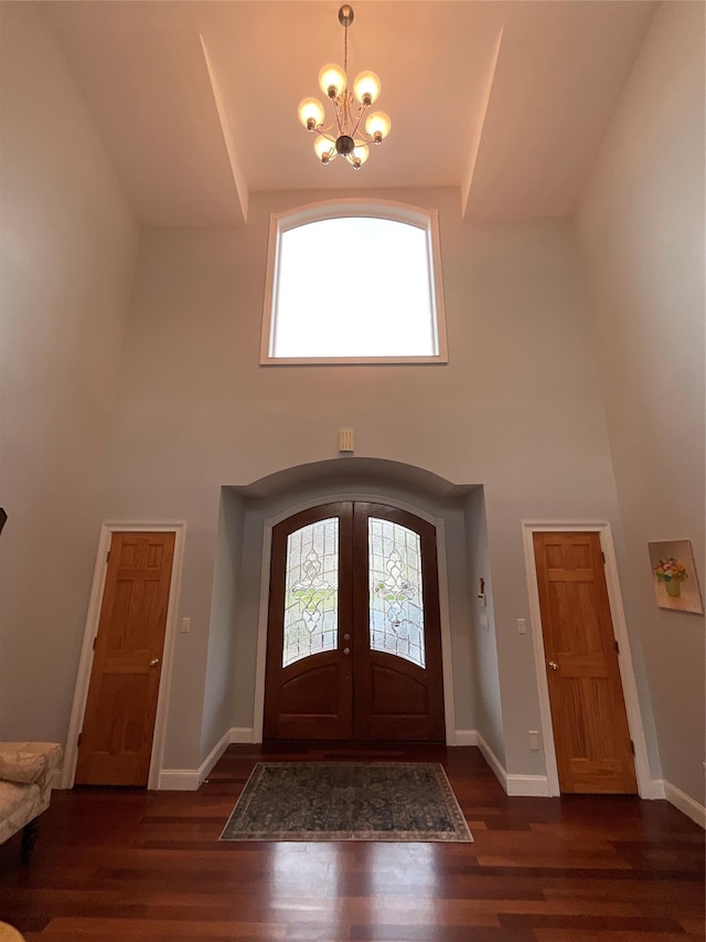 foyer entrance featuring a notable chandelier, a healthy amount of sunlight, wood finished floors, and a towering ceiling