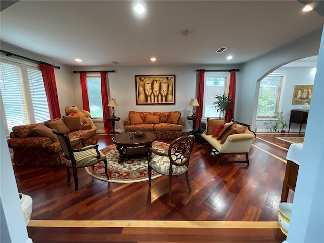 living room with dark wood finished floors, arched walkways, visible vents, and recessed lighting