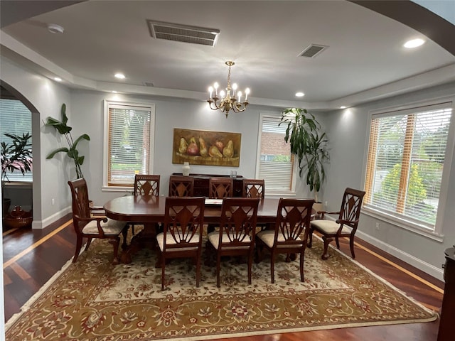 dining room with arched walkways, wood finished floors, visible vents, and baseboards