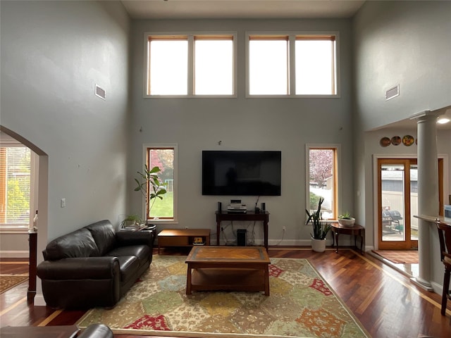 living room featuring visible vents, wood finished floors, a high ceiling, and arched walkways