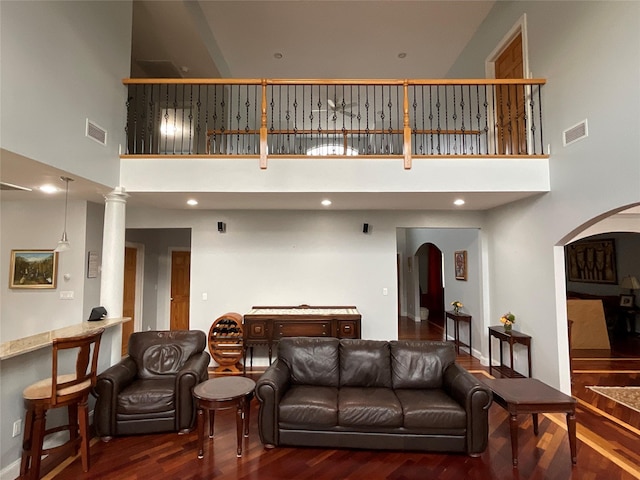 living area with a high ceiling, arched walkways, and visible vents