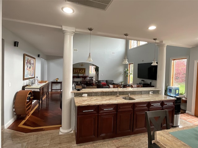 kitchen featuring visible vents, light stone countertops, decorative columns, hanging light fixtures, and open floor plan