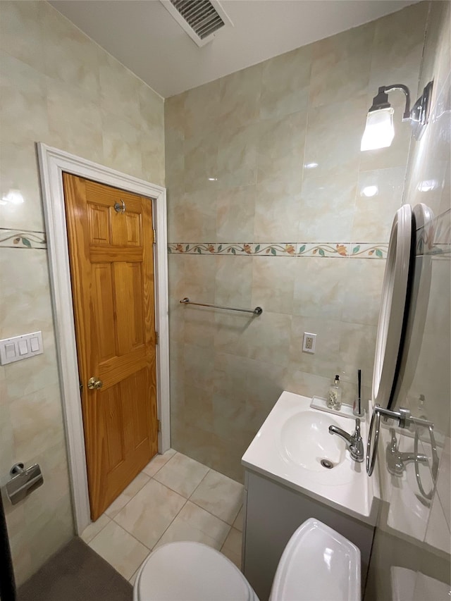 bathroom featuring tile patterned floors, visible vents, toilet, vanity, and tile walls