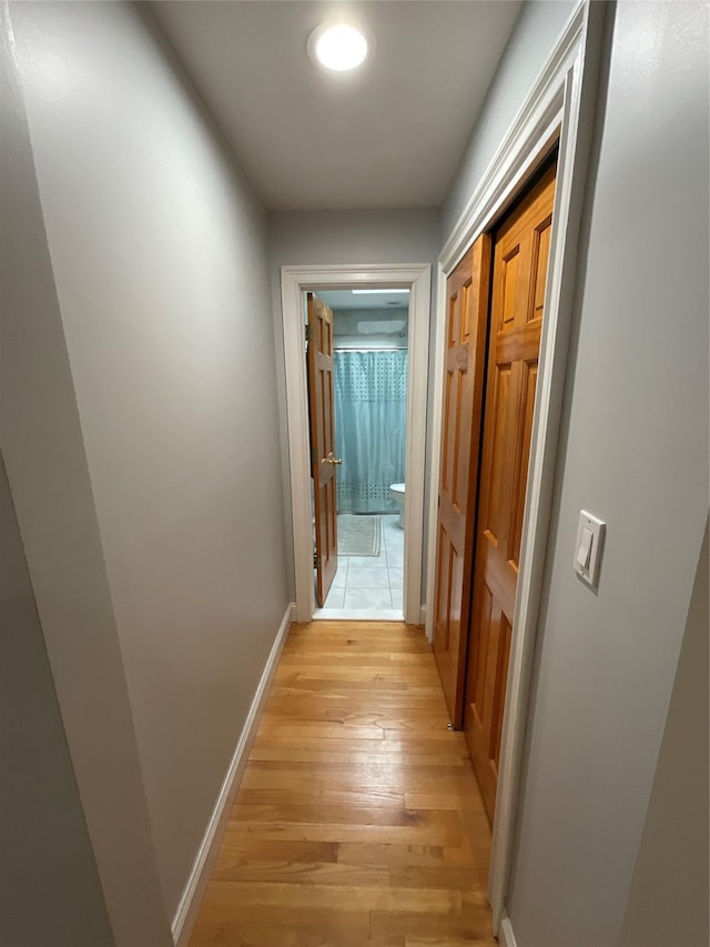 hall with light wood-style floors and baseboards