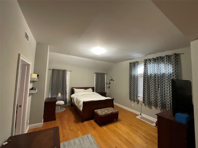 bedroom featuring vaulted ceiling, wood finished floors, visible vents, and baseboards