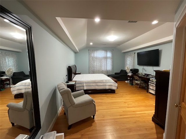 bedroom with vaulted ceiling, visible vents, light wood finished floors, and baseboards