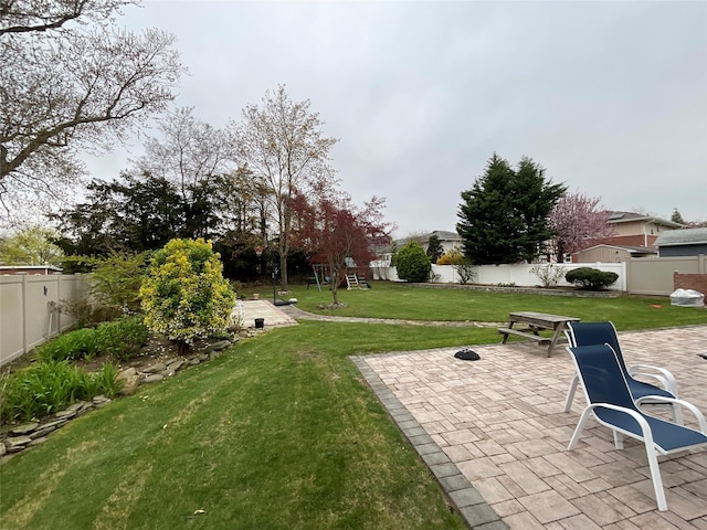 view of yard featuring a fenced backyard, a patio, and a playground