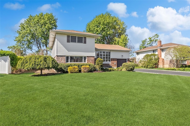 view of front of house with brick siding, an attached garage, driveway, and a front yard