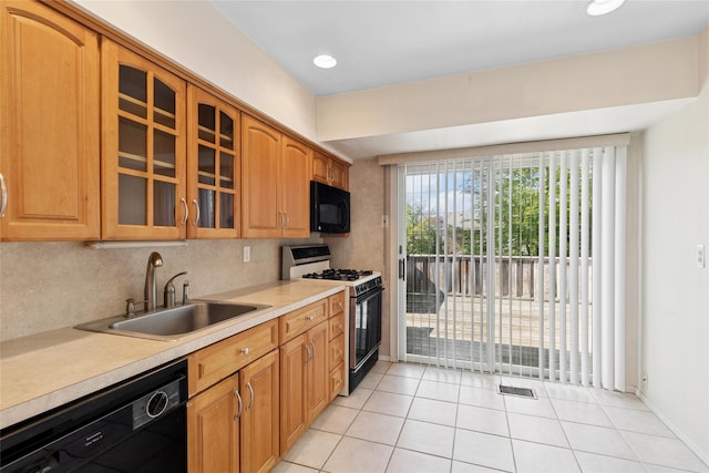 kitchen featuring visible vents, glass insert cabinets, light countertops, a sink, and black appliances