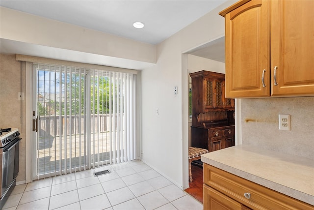 kitchen featuring visible vents, electric range, light countertops, tasteful backsplash, and light tile patterned floors