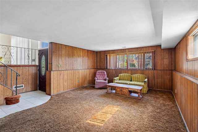 sitting room featuring stairway, carpet, wood walls, and visible vents