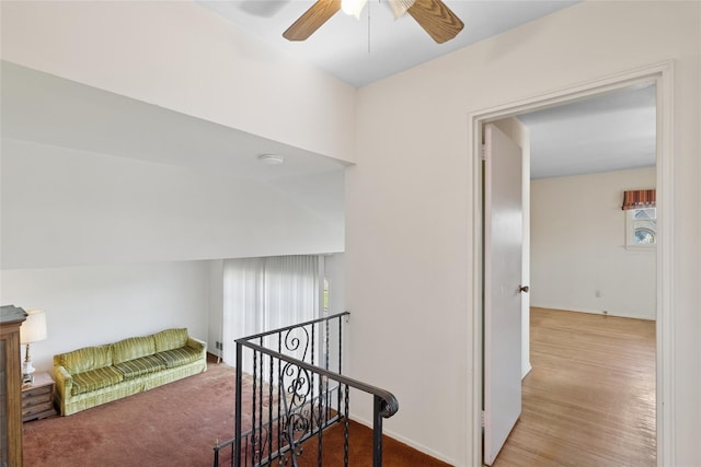 hall with baseboards, wood finished floors, and an upstairs landing