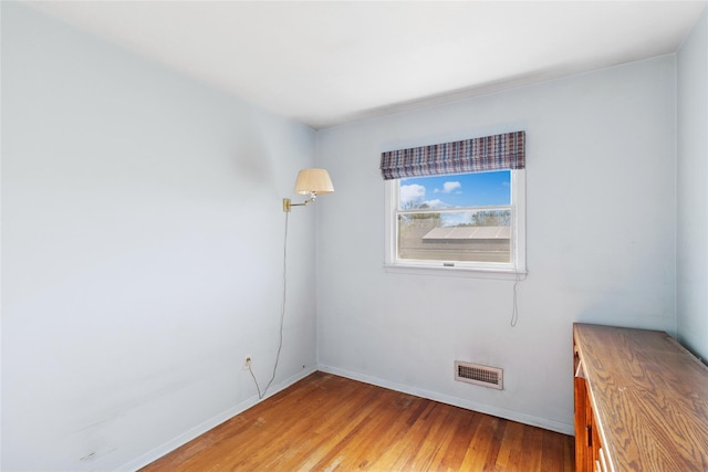 unfurnished room featuring visible vents, light wood-style flooring, and baseboards