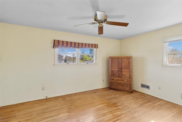 spare room featuring baseboards, ceiling fan, light wood finished floors, and visible vents