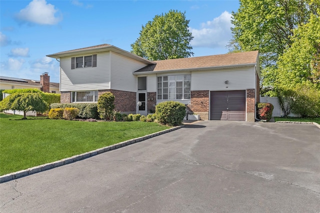 split level home with brick siding, an attached garage, driveway, and a front lawn