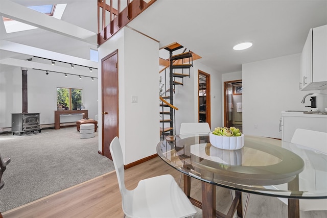 200 Fort Hill Rd, Scarsdale, NY 10583 - dining space featuring stairs, a skylight, light wood-style floors, a wood stove, and baseboards