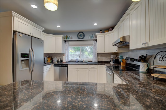 25 Evergreen Rd, Putnam Valley, NY 10579 - kitchen with dark stone countertops, appliances with stainless steel finishes, white cabinetry, backsplash, and under cabinet range hood