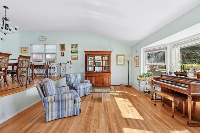 living area with light wood-style floors, vaulted ceiling, a healthy amount of sunlight, and a notable chandelier