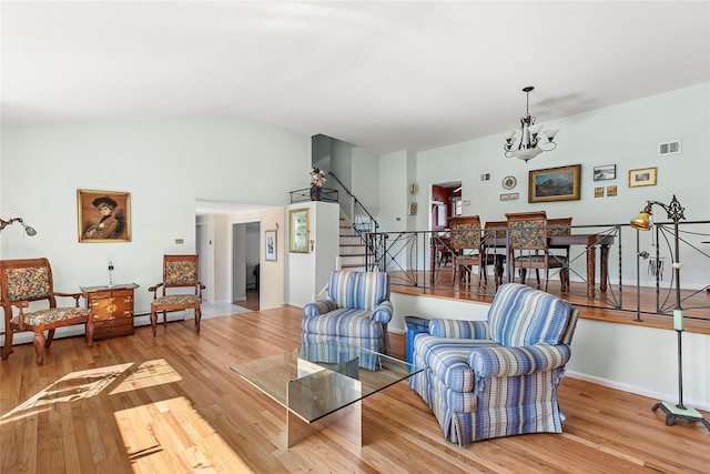 living room featuring stairway, a notable chandelier, wood finished floors, and visible vents