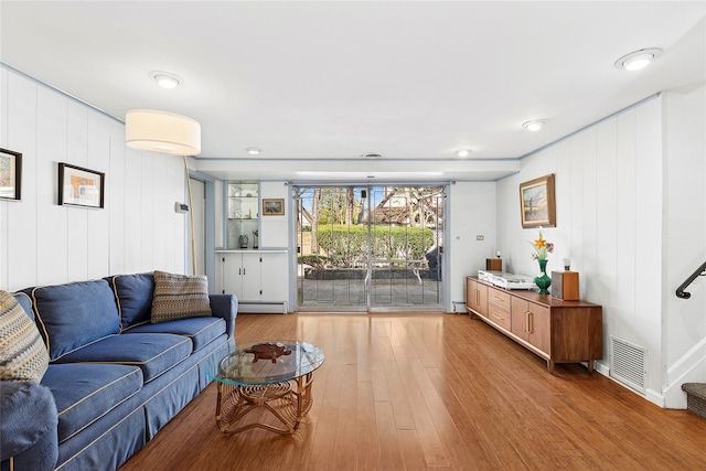living room featuring a baseboard radiator, wood finished floors, and visible vents