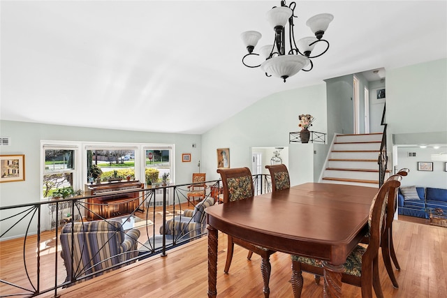 dining area with vaulted ceiling, visible vents, light wood-style flooring, and an inviting chandelier