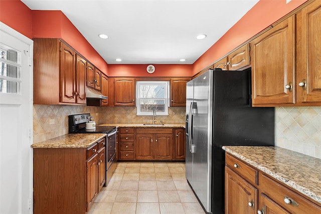 kitchen featuring brown cabinetry, under cabinet range hood, a sink, and appliances with stainless steel finishes