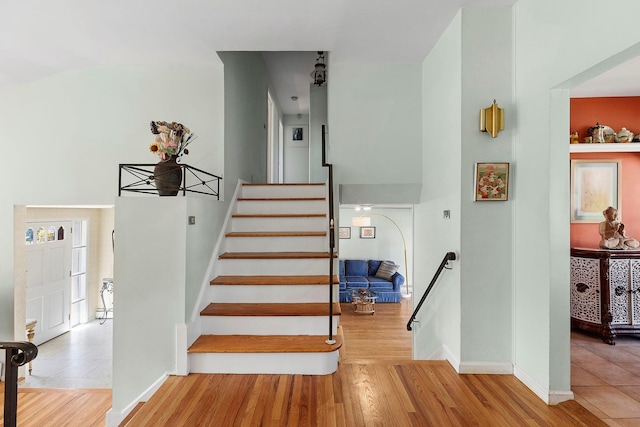 staircase with wood finished floors, baseboards, and plenty of natural light
