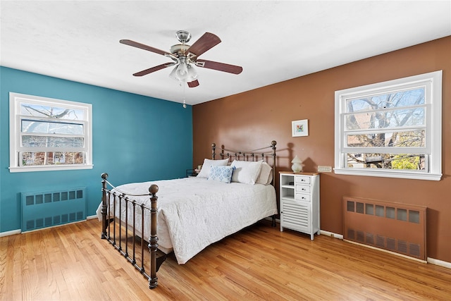 bedroom with radiator heating unit, baseboards, and light wood-type flooring