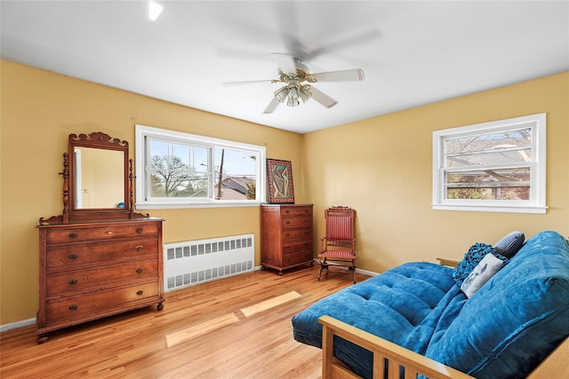 sitting room featuring a ceiling fan, baseboards, radiator heating unit, and wood finished floors