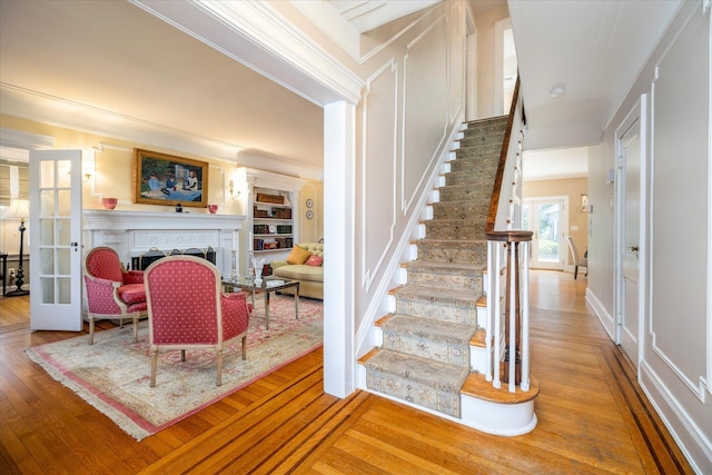 169 Hempstead Ave, Rockville Centre, NY 11570 - staircase with a decorative wall, ornamental molding, wood finished floors, and a fireplace