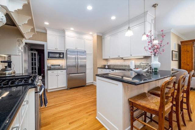 169 Hempstead Ave, Rockville Centre, NY 11570 - kitchen with dark countertops, decorative backsplash, a peninsula, light wood-style flooring, and appliances with stainless steel finishes