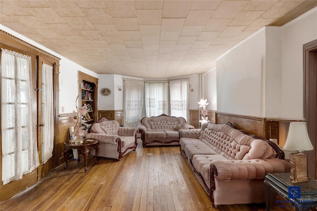 living room featuring wood-type flooring, ornamental molding, and wainscoting