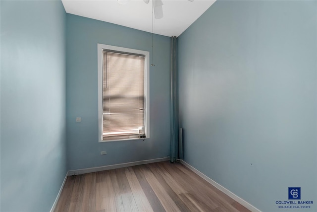 spare room featuring wood finished floors, baseboards, and ceiling fan