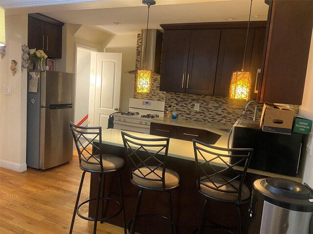 1255 E 223rd St, Bronx, NY 10466 - kitchen with freestanding refrigerator, white range with gas stovetop, exhaust hood, dark brown cabinetry, and a peninsula