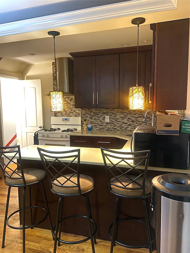 1255 E 223rd St, Bronx, NY 10466 - kitchen with wall chimney exhaust hood, dark brown cabinets, a kitchen breakfast bar, and white range with gas cooktop